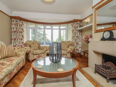 A living room with sofas a round glass coffee table and a fireplace at Nairn in Braunton