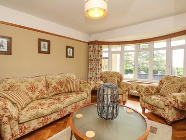 A living room with floral patterned sofas and armchairs around a round glass coffee table at Nairn in Braunton