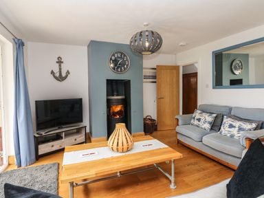 A living room with a wood stove fireplace television and sofas at Nairn in Braunton