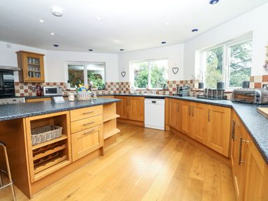 A kitchen with wooden cabinets black countertops and windows overlooking greenery at Nairn in Braunton