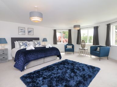A bedroom with a large bed and blue furniture at Nairn in Braunton