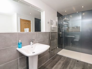 A bathroom with a pedestal sink a mirror a towel rack and a walk-in shower at Nairn in Braunton
