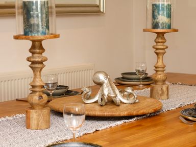 A dining table with plates glassware wooden candle holders and a decorative octopus at Nairn in Braunton