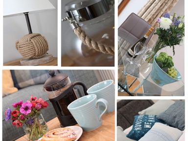 Close up of a table lamp a glass jug a glass table with a bottle and glasses a coffee press with cups and flowers and cushions on a sofa at Hazel Barn in Falmouth
