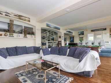A room with two sofas with cushions a glass coffee table and a pool table in the background at Bight Boathouse Dartmouth