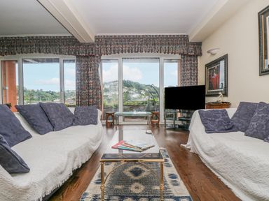 A living room with two sofas and a glass coffee table facing a television and large sliding glass doors at Bight Boathouse in Dartmouth