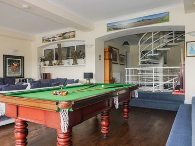 A room with a pool table a blue sofa a spiral staircase and decorative items at Bight Boathouse Dartmouth