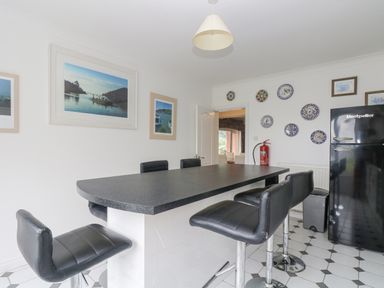A kitchen with a black countertop table and black leather stools with framed pictures and decorative plates on the wall at Bight Boathouse in Dartmouth