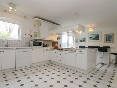 A kitchen with white cabinets a stove microwave dishwasher and a dining table with black chairs at Bight Boathouse in Dartmouth