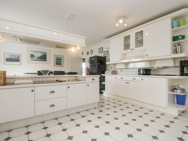 A kitchen with white cabinets a black refrigerator and a tiled floor at Bight Boathouse in Dartmouth