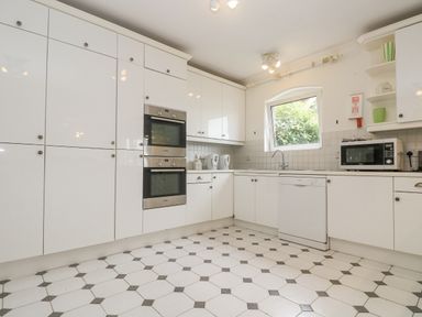 A kitchen with white cabinets a double oven a dishwasher a microwave and a window at Bight Boathouse Dartmouth