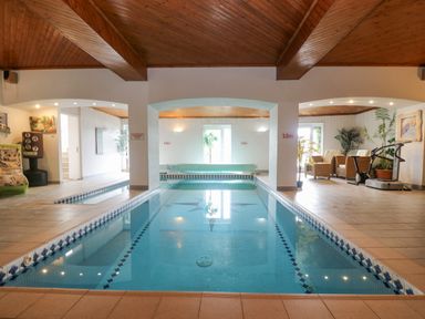 An indoor swimming pool with tiled floor and ceiling a punching bag seating area exercise bike and plants at Bight Boathouse in Dartmouth