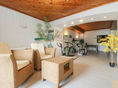 A room with wicker chairs and table adjacent to exercise equipment at Bight Boathouse in Dartmouth