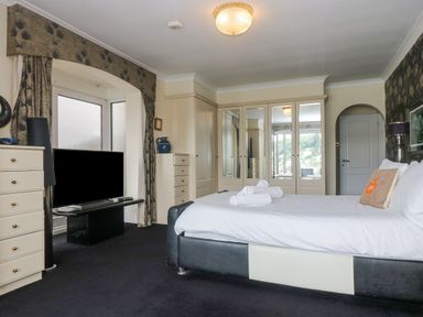 A bedroom with a bed towels on it wardrobes with mirrored doors a television and cabinets at Bight Boathouse Dartmouth