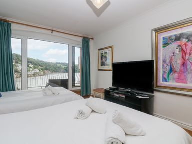 A bedroom with two beds and rolled towels facing a television and large window with a view at Bight Boathouse in Dartmouth