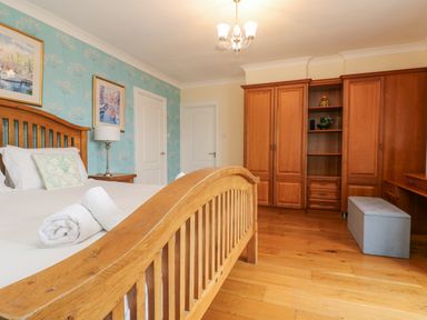 A bedroom with a wooden bed and wardrobe and a blue ottoman at Bight Boathouse in Dartmouth