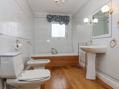 A bathroom with toilet bidet bathtub and sink with wooden floor at Bight Boathouse in Dartmouth