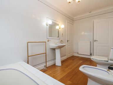 A bathroom with a bathtub sink toilet bidet mirror and wooden floor at Bight Boathouse in Dartmouth