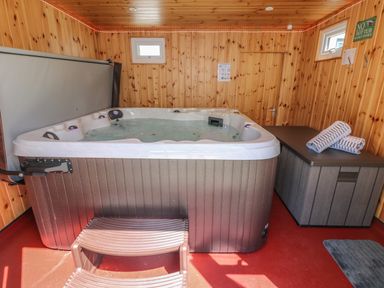 A wooden room with a hot tub two windows towels on a cabinet and a no hot tub sign at Hagar Vor in Marazion