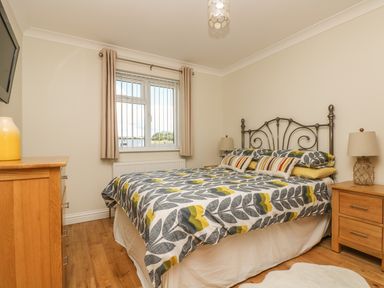 A bedroom with a bed with patterned bedding between wooden bedside tables at Hagar Vor in Marazion