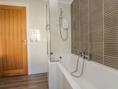 A bathroom with a bathtub shower fixture and tiled walls at Hagar Vor in Marazion