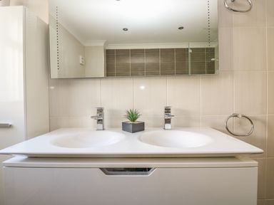 A bathroom with a double sink vanity a large mirror and a small potted plant at Hagar Vor in Marazion