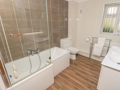 A bathroom with a bathtub shower toilet double sink and towel rack at Hagar Vor in Marazion