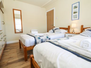 A bedroom with two single beds with striped pillows and folded towels at Higher Mount View in Marazion