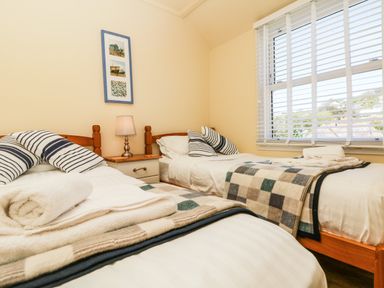 A bedroom with two single beds white linens and checkered blankets at Higher Mount View in Marazion