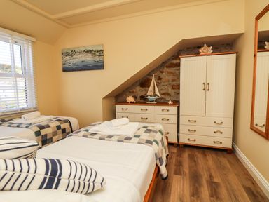 A bedroom with two single beds a chest of drawers and a wardrobe at Higher Mount View in Marazion