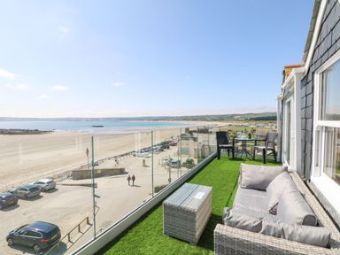 A balcony with outdoor furniture overlooking a beach and coastline at Higher Mount View in Marazion