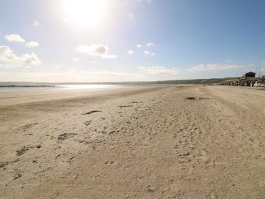 A sandy beach with footprints and a small building on the right side at Higher Mount View in Marazion