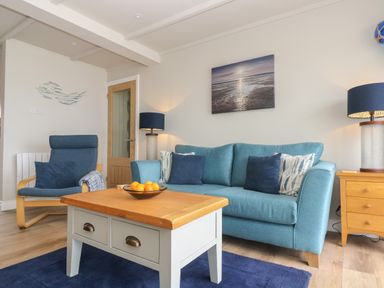 A living room with a blue sofa blue armchair wooden coffee table and lamps at Higher Mount View in Marazion