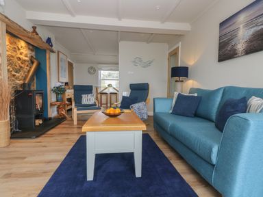 A living room with blue sofa and chairs a wooden coffee table and a fireplace at Higher Mount View in Marazion