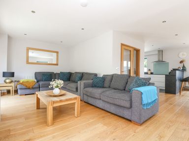 A living room with gray sofas and a wooden coffee table with flowers at Lake View in Kingsand and Cawsand