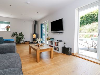 A living room with a wood stove a television on the wall a coffee table and sliding glass doors at Lake View in Kingsand and Cawsand