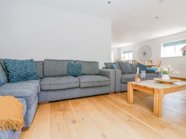 A living room with grey sofas and blue cushions and a wooden coffee table with flowers at Lake View in Kingsand and Cawsand