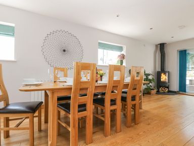 A dining room with a wooden table set for six chairs a wood burning stove and wall decor at Lake View in Kingsand and Cawsand