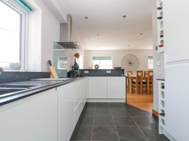 A kitchen with white cabinets black countertops a knife block a toaster and a dining area with a wooden table and chairs at Lake View in Kingsand and Cawsand