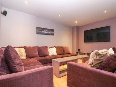 A living room with purple sofas a coffee table and a wall mounted tv at Lake View in Kingsand and Cawsand