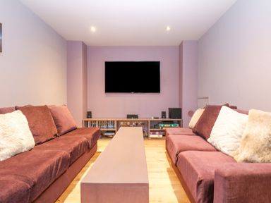 A living room with two purple sofas facing a wall mounted TV and a long coffee table at Lake View in Kingsand and Cawsand
