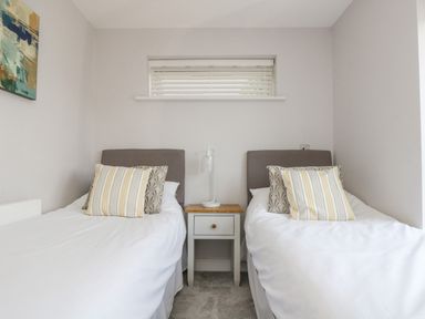 A bedroom with two single beds a nightstand and a window at Lake View in Kingsand and Cawsand