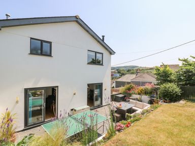 A backyard with a patio table tennis table garden furniture and flowers at Lake View in Kingsand and Cawsand
