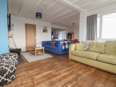 A living room with two sofas a wooden coffee table and a rug at Gwillen in Mawgan Porth