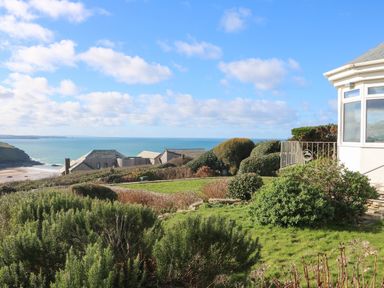 Garden with bushes and hedges overlooking houses and a beach by the sea at Gwillen in Mawgan Porth