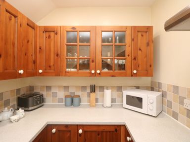 A kitchen countertop with a toaster paper towel holder microwave and wooden cabinets at Goslings Bradford Holsworthy