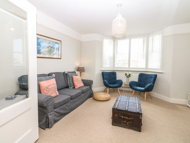 A living room with a grey sofa and blue chairs around a wooden chest in Cool Stone Cottage Instow near Bideford