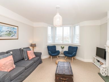 A living room with a gray sofa and blue chairs around a wooden trunk as a coffee table at Cool Stone Cottage Instow near Bideford