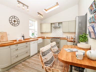 A kitchen with wooden countertops cabinets a stove and a dining table with chairs at Cool Stone Cottage Instow near Bideford