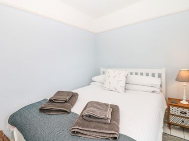 A bedroom with a double bed with towels on it and a bedside table with a lamp at Cool Stone Cottage in Instow near Bideford